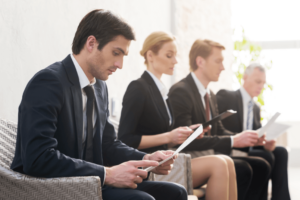 Professionals waiting for a job interview, reviewing documents and preparing for the hiring process in a corporate setting.