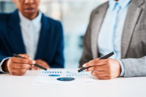 Business professionals reviewing charts and data, discussing strategy and analyzing financial reports during a meeting.