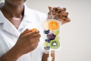 Close-up of a healthcare professional preparing an IV hydration bag infused with fresh fruits, symbolizing vitamin and nutrient therapy.