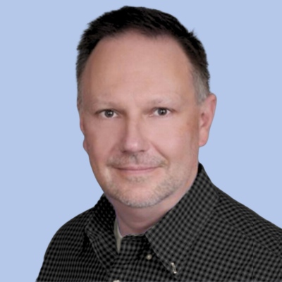 Headshot of a middle-aged man with short hair wearing a checkered shirt, posing against a light blue background.