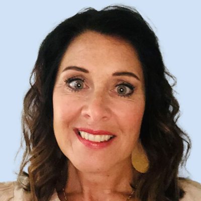 Headshot of a smiling professional woman with dark wavy hair and wearing light makeup, set against a light blue background.